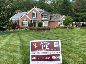 montgomery county roof installation from politz enterprises showing company sign and three story house in the background with crew members mid project
